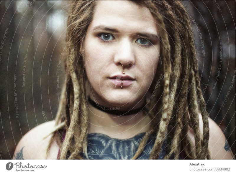 Portrait of a young woman with dreadlocks and tattoos in the forest - a Royalty Free Stock Photo from Photocase