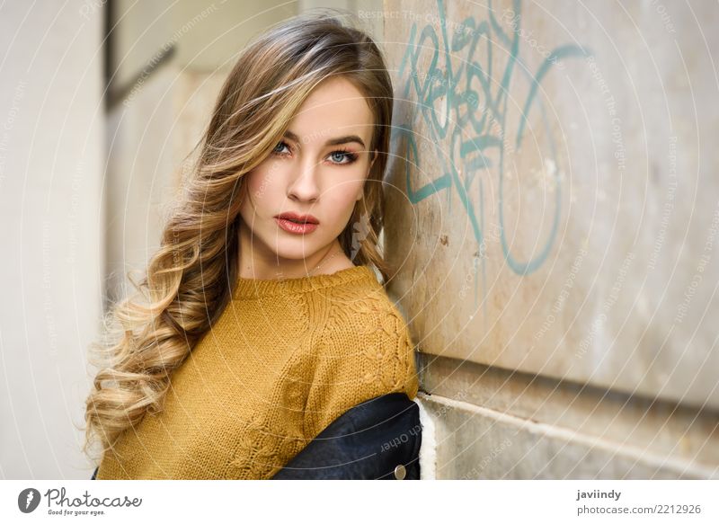 Beautiful young caucasian woman in urban background. Blond girl