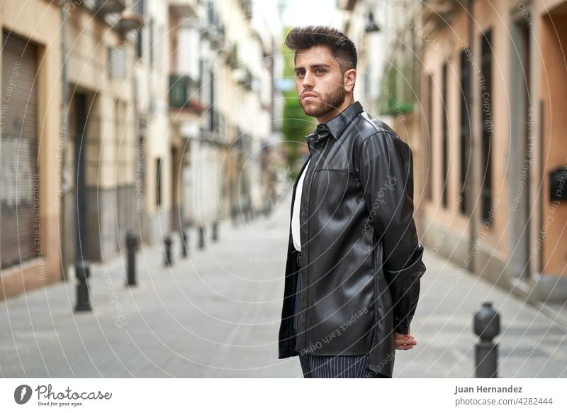 Bearded man wearing black leather jacket and sunglasses adjusting