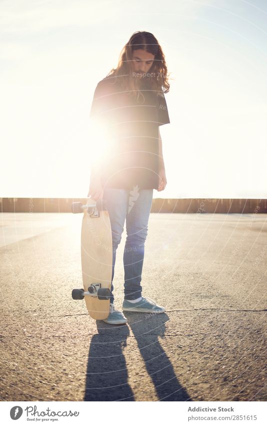 Man posing with skateboard in evening Royalty Stock Photo from Photocase