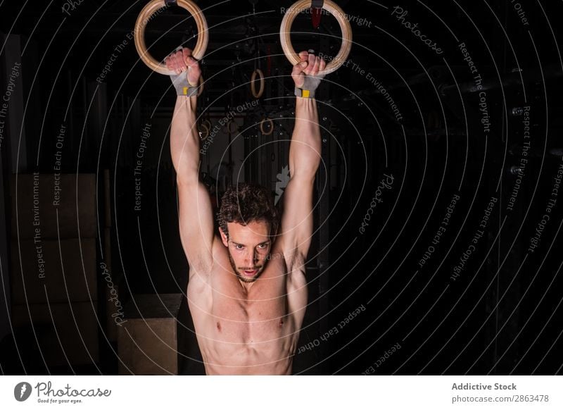 Man, acrobat and gymnastics upside down on rings in fitness for practice,  training or workout at gym. Professional male gymnast hanging on ring  circles for athletics, acrobatics or strength exercise Stock Photo