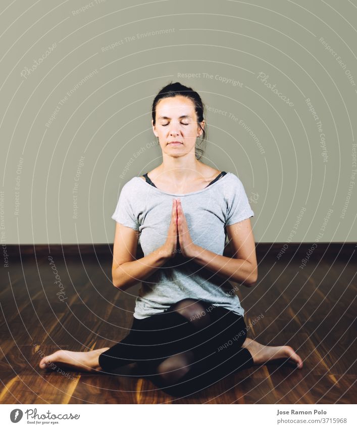 Yogi meditating while sitting cross-legged on carpet at health club stock  photo